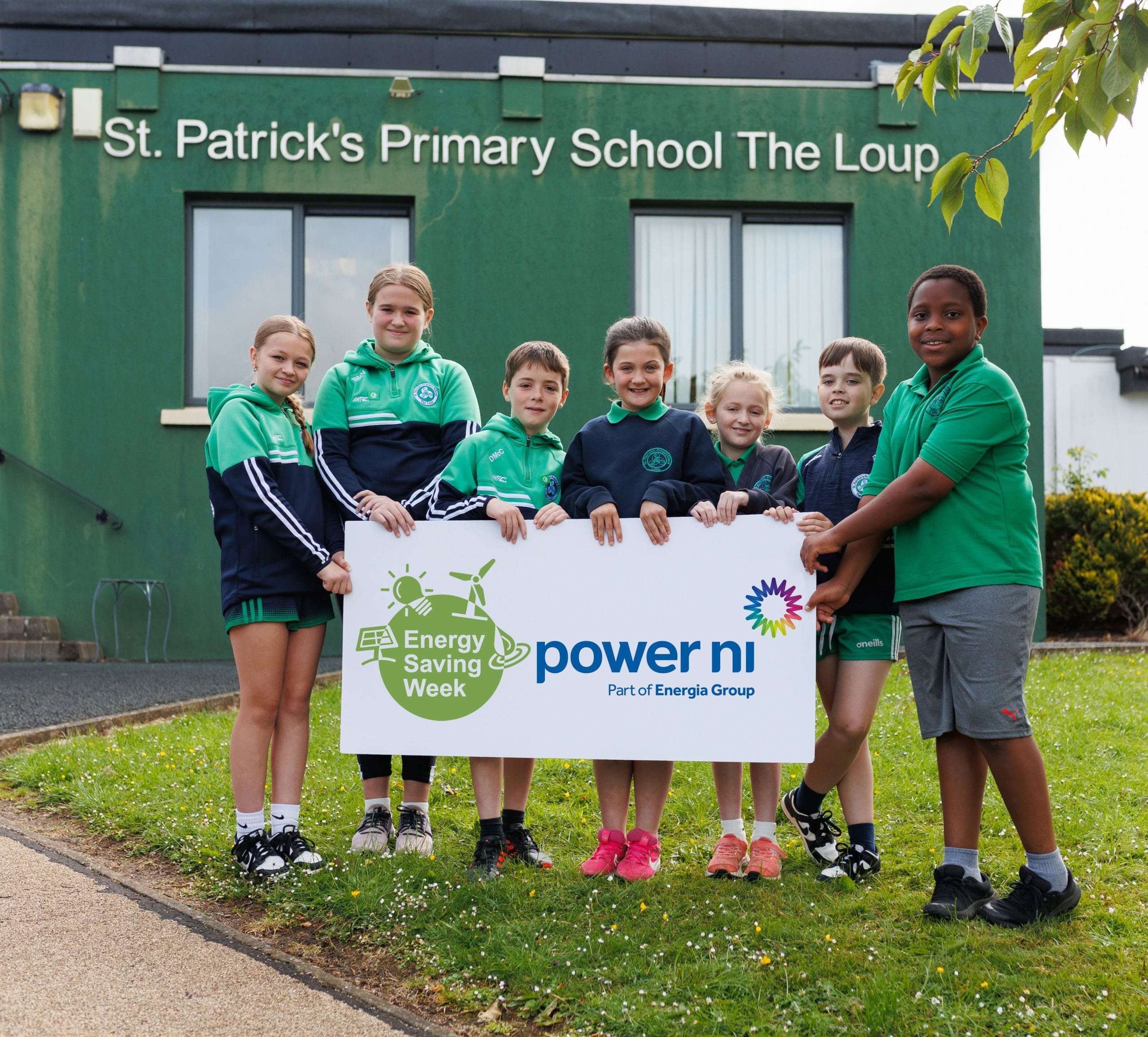 Seven primary school pupils holding a sign for Energy Saving Week and Power NI