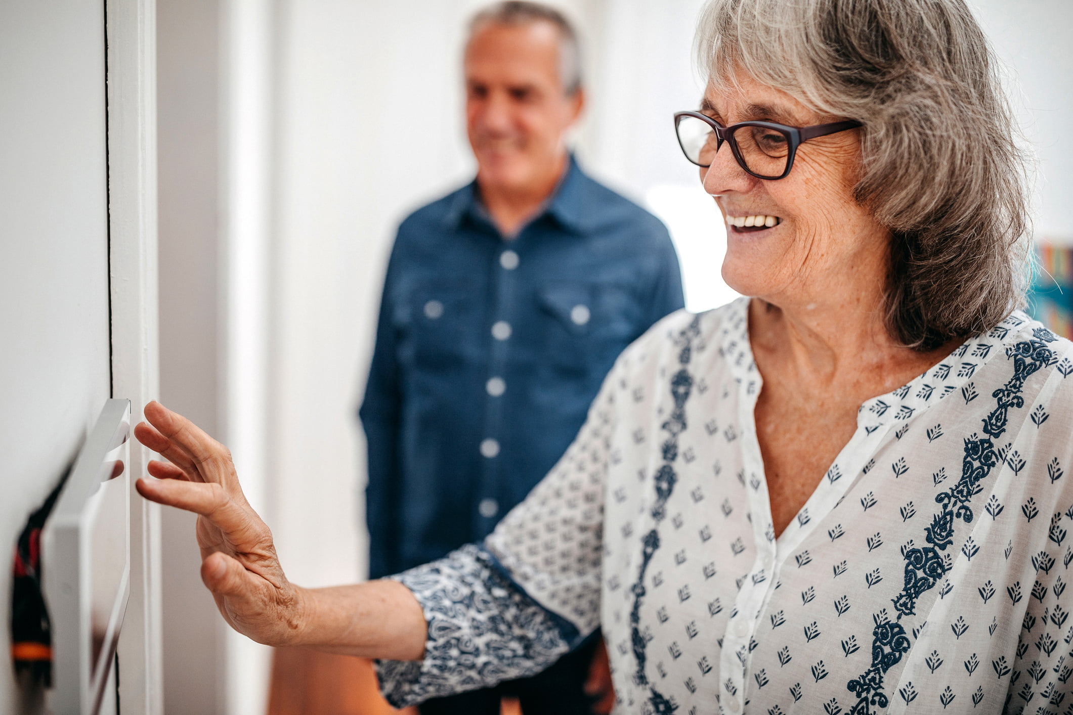 Senior woman using home automation touch screen panel in nursing home