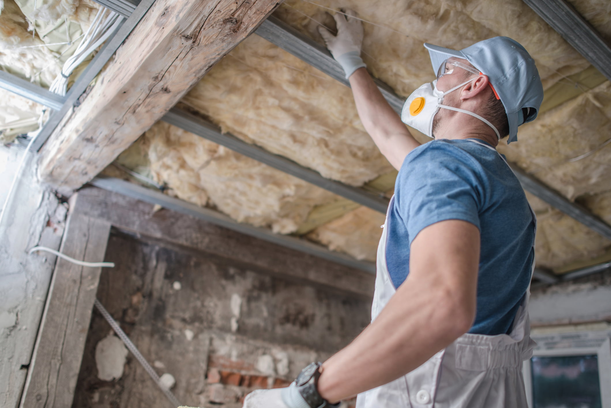 Workman replacing old attic mineral wool insulation.