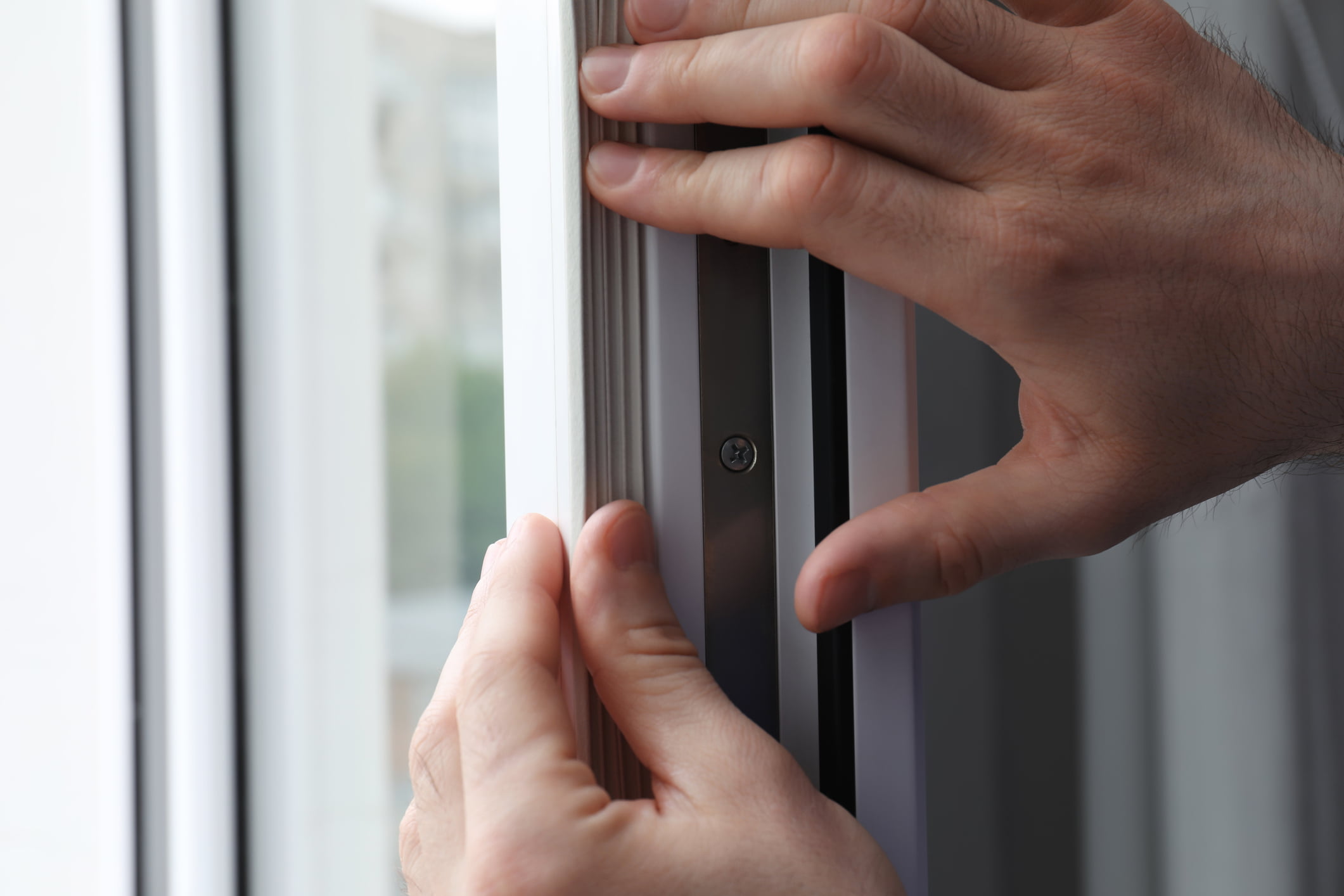 Worker putting rubber draught strip onto window indoors, closeup