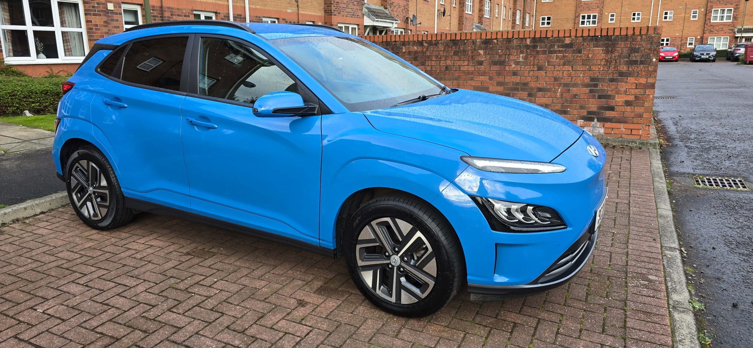 a blue electric car parked on a paved driveway
